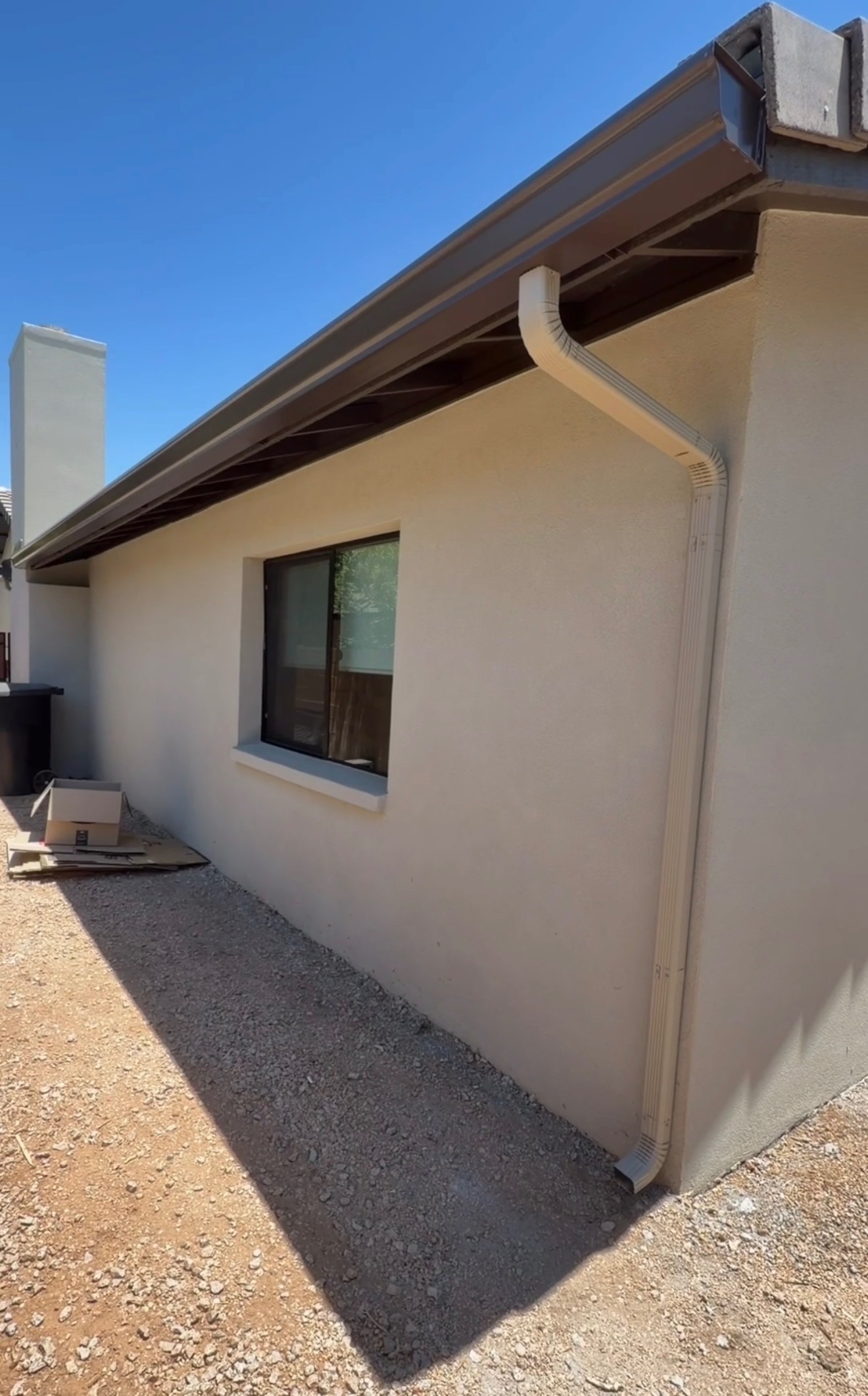 Seamless rain gutter run along the roofline with a white downspout installed by Wally's
